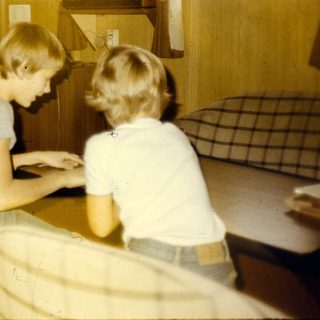 Office setting with woman typing, two children working at desk.
