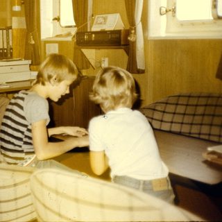 Office setting with woman typing, two children working at desk.