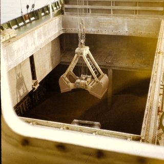 Cargo hold with clamshell loader lifting material.