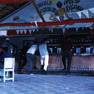Busy bar interior with patrons and bartenders.