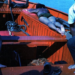 Boat with person sunbathing on deck.