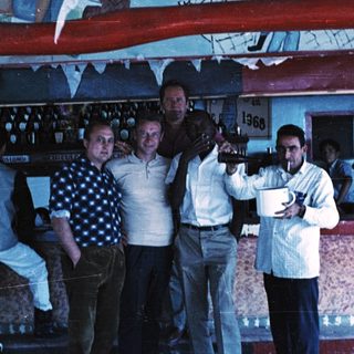Group of men posing happily at a bar.