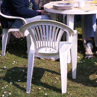 Three men sitting outdoors with a dog, relaxing at a small table.