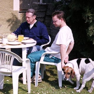 Four people eating outdoors with a dog.