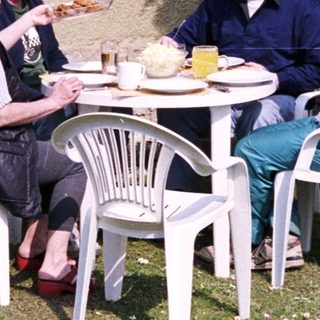Four people eating outdoors with a dog.