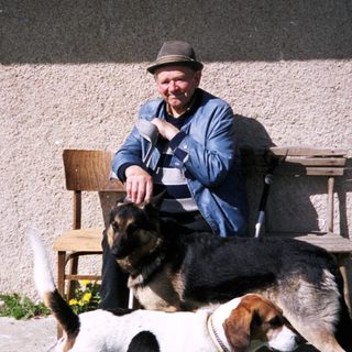 Man sitting with two dogs outside a building.
