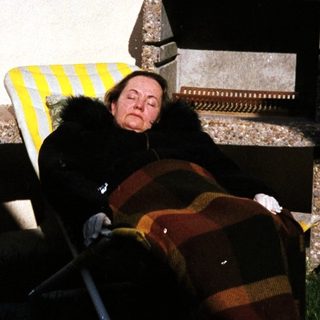 Person relaxing on striped outdoor chair near fireplace.
