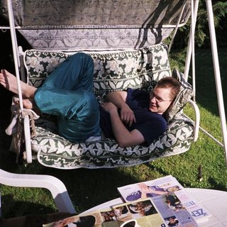 Person lounging in a hanging chair outdoors.