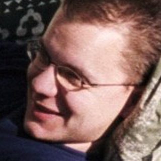 Person lounging in a hanging chair outdoors.
