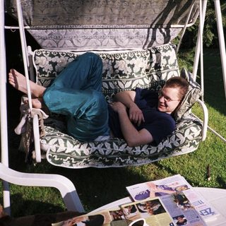 Person lounging in a hanging chair outdoors.
