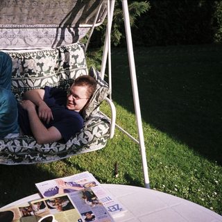Person lounging in a hanging chair outdoors.