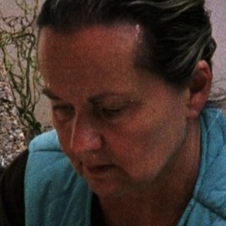 Woman preparing food by outdoor fireplace.