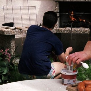 Woman preparing food by outdoor fireplace.