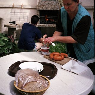 Woman preparing food by outdoor fireplace.