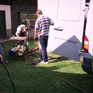 People washing camper van exterior with hoses.