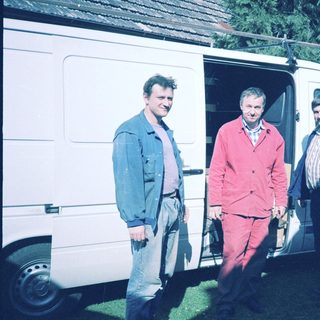 Three men standing by an open van.