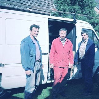 Three men standing by an open van.