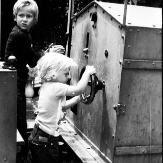Two children opening a large metal hatch.
