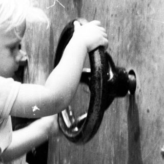 Two children opening a large metal hatch.