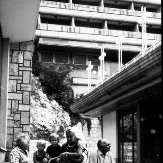 Family sitting on steps outside residential building.