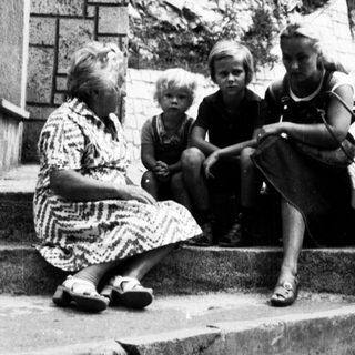 Family sitting on steps outside residential building.