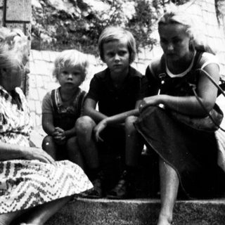 Family sitting on steps outside residential building.