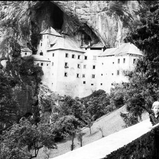 Child standing near cliffside castle.
