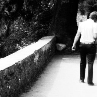 Child standing near cliffside castle.