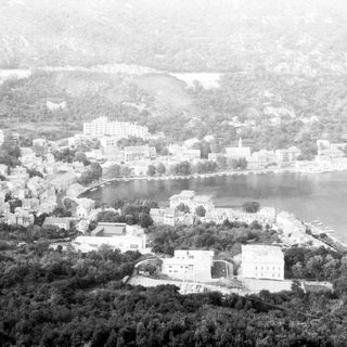 Historic coastal town with lakeside buildings and hills.