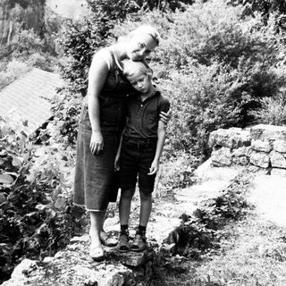 Mother and child standing near historic mountain castle.