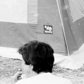 Camping scene with tent and parked camper van.