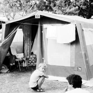 Camping scene with tent and parked camper van.
