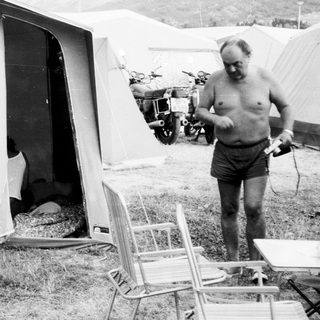 Two people relaxing at a campsite tent.
