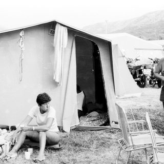 Two people relaxing at a campsite tent.