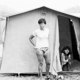 Family camping in tent at outdoor site.