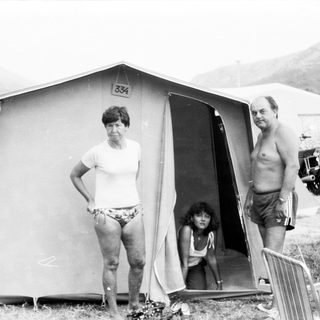 Family camping in tent at outdoor site.