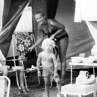 Family camping outdoors near tent with car.