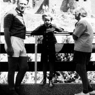 Three people posing near historic bunkers on elevated platform.