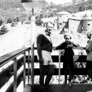 Three people posing near historic bunkers on elevated platform.