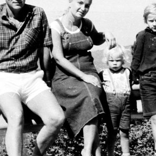 Family posing outdoors near mountainous roadside.
