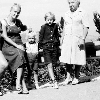 Family posing outdoors near mountainous roadside.