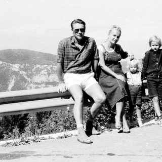 Family posing outdoors near mountainous roadside.