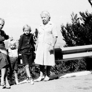 Family posing outdoors near mountainous roadside.