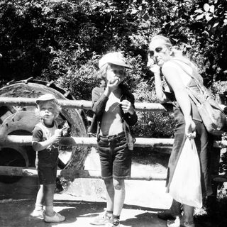 Family enjoying outdoor water play with old-fashioned equipment.