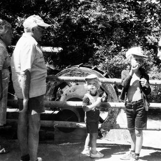 Family enjoying outdoor water play with old-fashioned equipment.