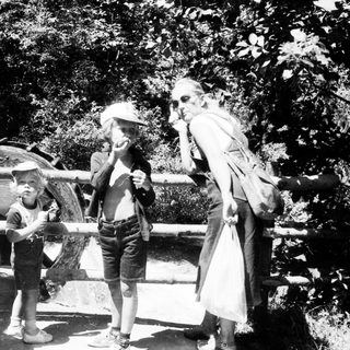 Family enjoying outdoor water play with old-fashioned equipment.