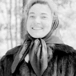 A cheerful person smiling in winter forest snow.