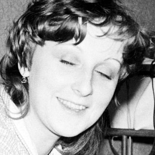 Woman smiling while writing or drawing at desk.