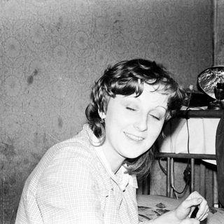 Woman smiling while writing or drawing at desk.