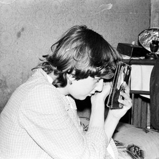 Person using early portable hair dryer indoors.